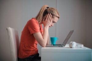 Young Woman sitting at a desk with her hands on her face staring at her computer