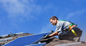 Installer putting solar panel on a roof to qualify for energy efficiency improvement tax credits