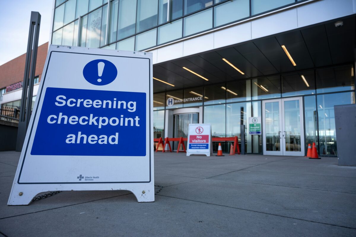 Picture of the front of a airport area with a placard that says screening ahead